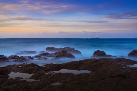 Long exposure view of the Sant'Antioco island coast and the Mangiabarche Lighthosue at sunrise on