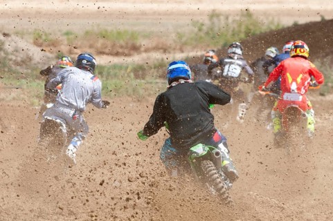 Unrecognized athletes riding a sports motorbike racing fast on a motocross track field. Challenge