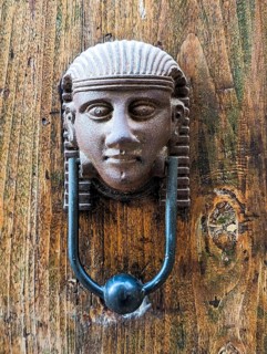 Vintage style doorknocker of an Egyptian head, a door in Italy