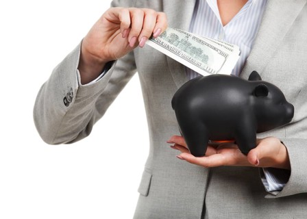 Businesswoman holding the piggy bank and dollar bills in her hands