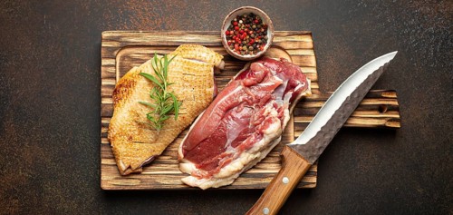 Two raw uncooked duck breast fillets with skin, seasoned with salt, pepper, rosemary top view on