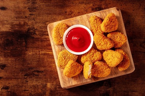Chicken nuggets with ketchup on a rustic wooden table, shot from the top with a place for text.
