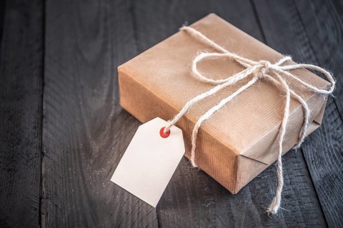Gift box, wrapped in brown vintage paper and tied with white flax string, on an old black wooden