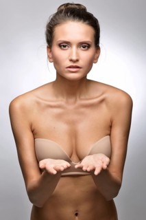 Beautiful woman in flesh color underwear showing by hand. Studio shooting