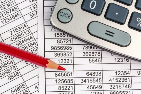 A calculator lies on the figures of a balance sheet and statistics. Symbol photo for turnover,