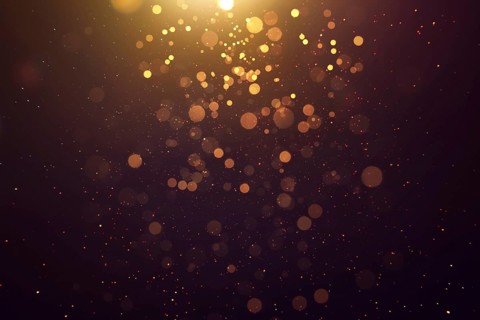 Abstract glittering gold with bokeh and dust effect . Black background
