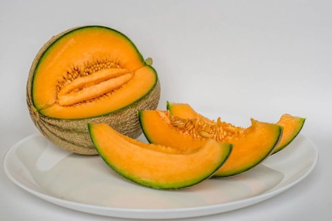 Cut cantaloupe with slices on white background