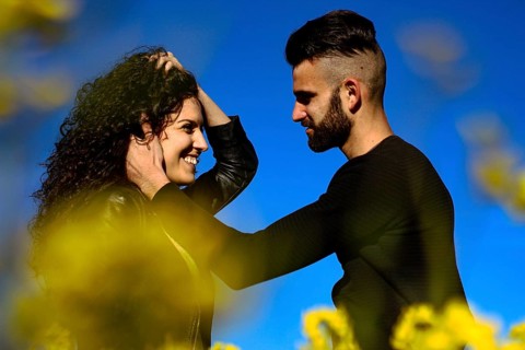 Portrait of a young smiling couple where hair man caresses his girlfriend's face before kissing