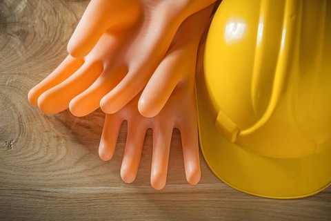 Safety building helmet electricians gloves on wood board