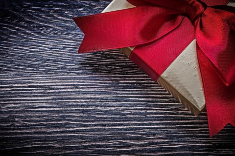 Tied wrapped gift box on wooden board holiday concept