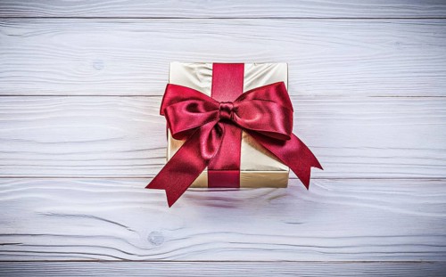 Golden gift-container with tied bow on wood board holidays concept