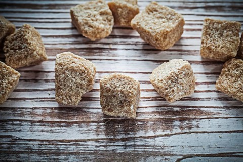 Vintage cane sugar cubes on wooden board top view