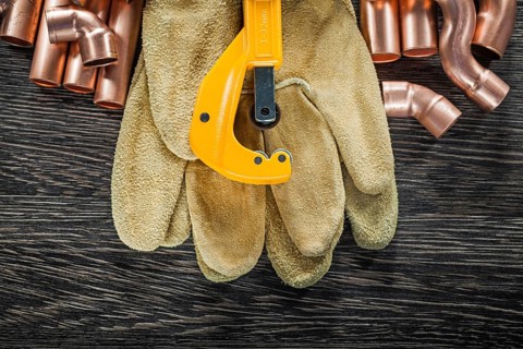 Plumbing copper water pipe scissors leather safety gloves on wooden board