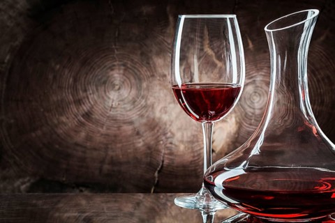 Very close up decanter and wineglass with red wine on vintage wooden background