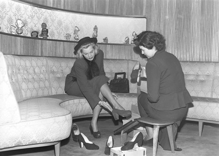 A young woman is well taken care of by a clerk in a shoe store. The dispatcher tries different