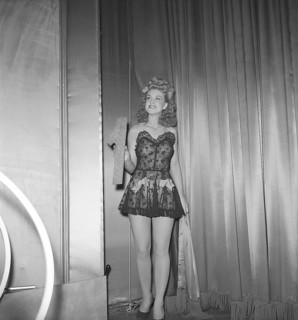 At the theatre in the 1940s. A young woman holds the number one in her hand on a theatre stage. It