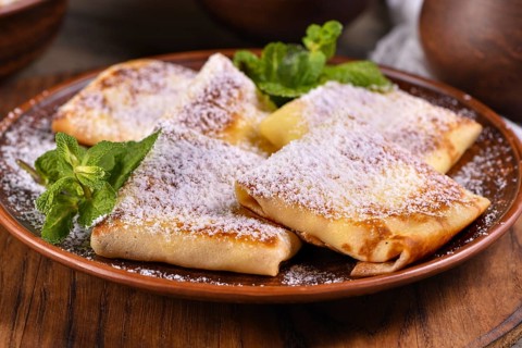 Thin pancakes filled with cottage cheese, honey and raisins, wrapped in an envelope, sprinkled with