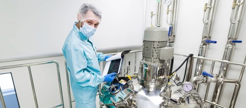 Widescreen picture, scientist in blue laboratory suit and gas mask stand in clean room and check