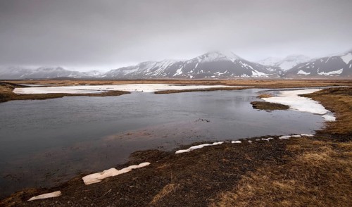 Typical Icelandic dramatic landscape with frozen lake and mountains covered in snow in Iceland
