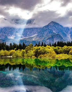The sun's rays break through the clouds. The lake Fusine in Northern Italy. Mountains covered in