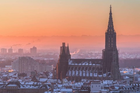 City Ulm in winter with fresh snow and fog. Mountains Alps in background with Minster
