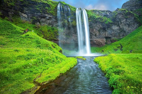 The warm July day in Iceland. Seljalandsfoss waterfall. Rainbow decorates drop of water