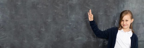Schoolgirl shows on an empty school board. He is standing in the classroom at the chalkboard.