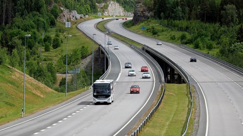 Summer motorway landscape with white Iveco Evadys tour bus among car traffic. Salo, Finland, June