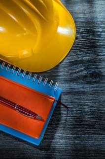 New notebooks pen safety building helmet on wooden board