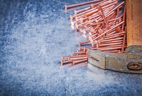 Vintage claw hammer copper construction nails on metallic background