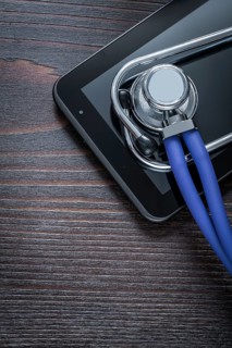 Medical stethoscope and touch-sensitive pad on vintage wooden background medicine concept