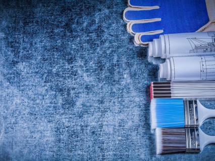 Copyspace of wooden meter paintbrushes protective gloves and rolled blueprints