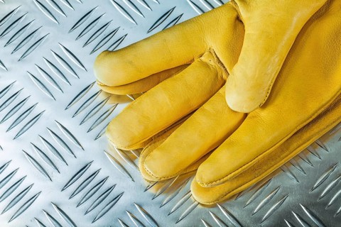 Pair of leather safety gloves on corrugated metal texture