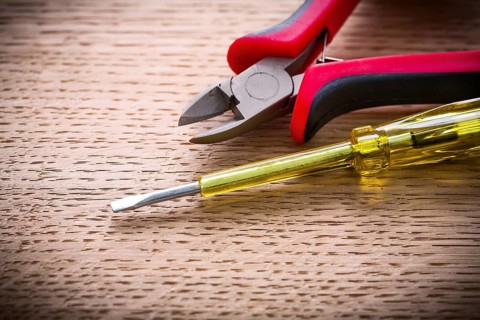 Very close up electrical tester and nippers on wooden board