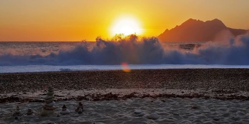 Land art in front of surf waves at sunset on Porto beach, Corsica