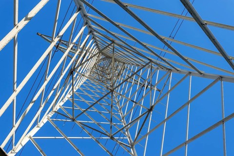 High Voltage Electricity Grid Pylon seen from below and blue sky