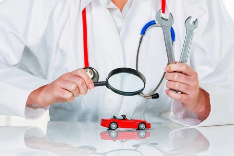 A model of a car is examined by a doctor. Symbol photo for workshop, service and car purchase.