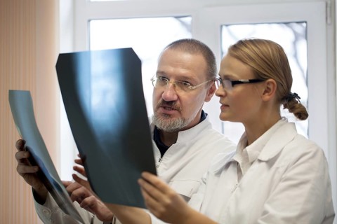 Senior and young doctors analyzing and dicussing the result of x-ray examination. They having two