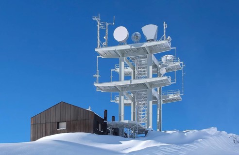 Communication antenna tower and satellite dishes against blue sky