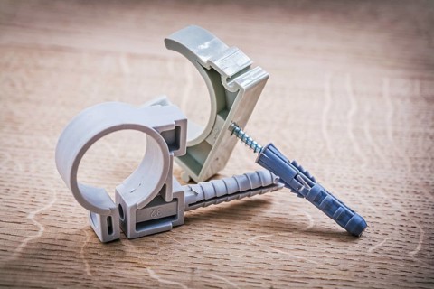 Plastic fixators for pipes On Wooden Board