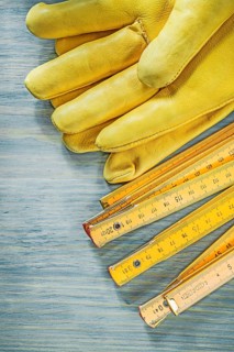 Wooden meter leather safety gloves on wood board construction concept