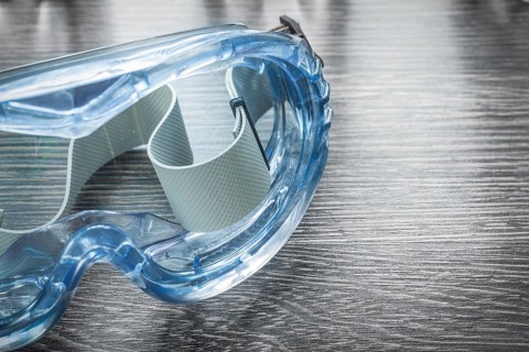 Safety plastic glasses on wooden board