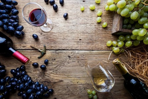 Red and white wine with glass, bottle and grapes over wooden background, copy space, top view