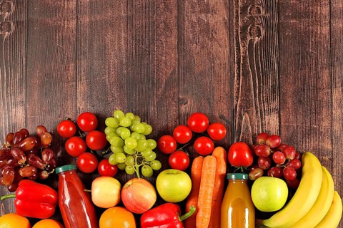 Trauben, Orangen, Tomaten, Äpfel, Bananen, Paprika und natürlichen Saft auf hölzernen Hintergrund,