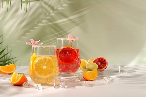 Royal cocktail of blood orange, lemon and lime, ice cubes, rum and tequila. Flyer with a glass of