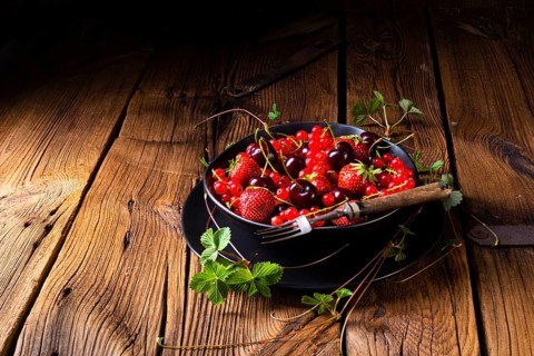 Schüssel mit verschiedenen Früchten wie Erdbeere, rote Johannisbeere und Kirsche