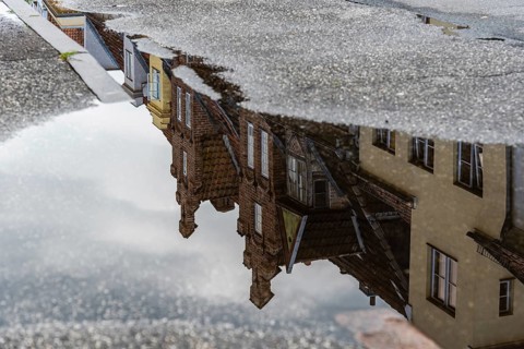Reflection on water puddle of colorful old gable houses in historic centre of Lubeck, Germany