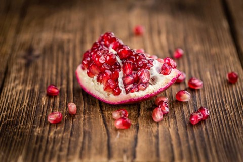 Pomegranate on an old wooden table as detailed close-up shot (selective focus)