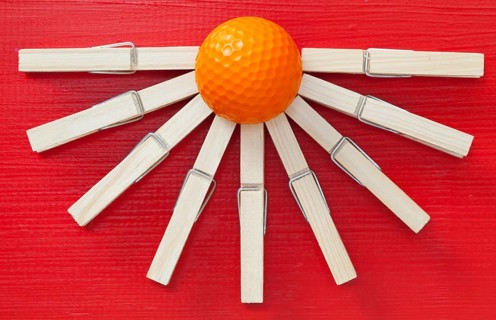Set of cloth pegs and golf ball on wooden red table