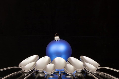 Blue Christmas decoration and nine spoons on a black glass desk